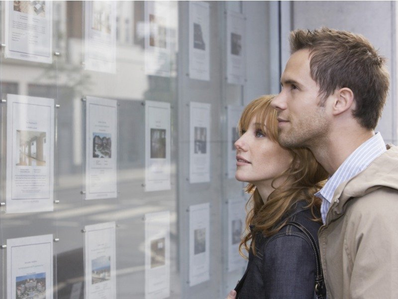 Giovane coppia guarda la vetrina di un'agenzia immobiliare